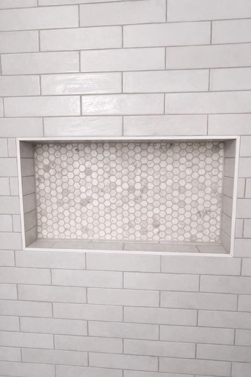 Recessed shower niche with white-frame and hexagon marble mosaic back