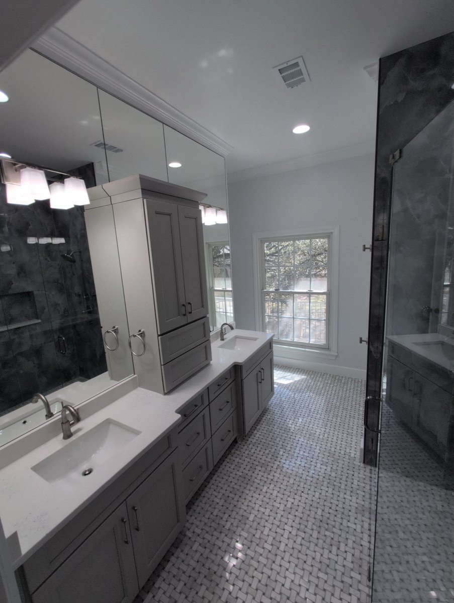 Gray double vanity with center tower below mirror and window with shutters