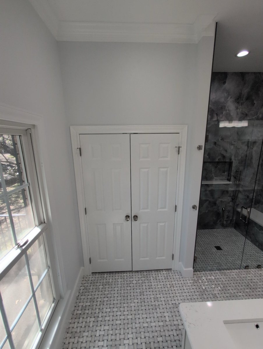 White six-panel closet doors beside the dark stone glass shower