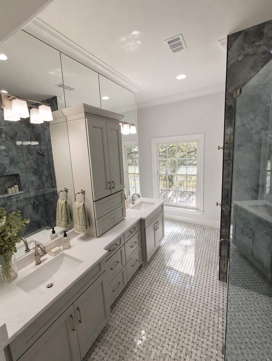 Gray double vanity with center tower and window beside the glass shower