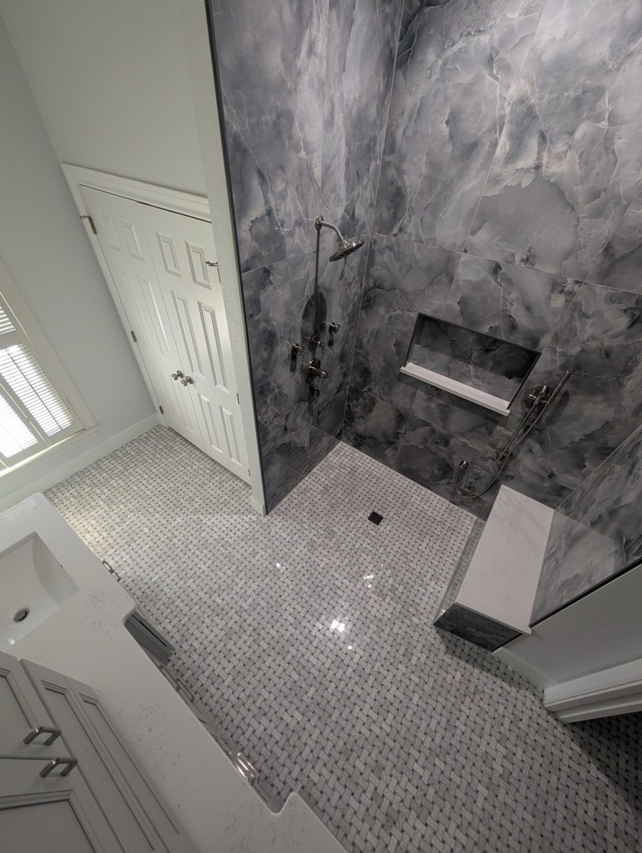 Overhead view of gray stone shower with niche and basketweave tile floor
