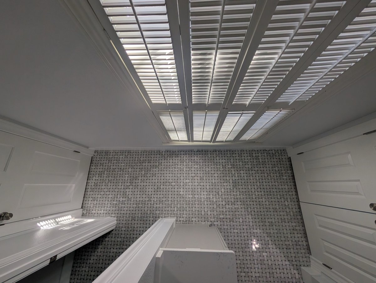 Plantation-shutter window above basketweave marble tile in the bathroom