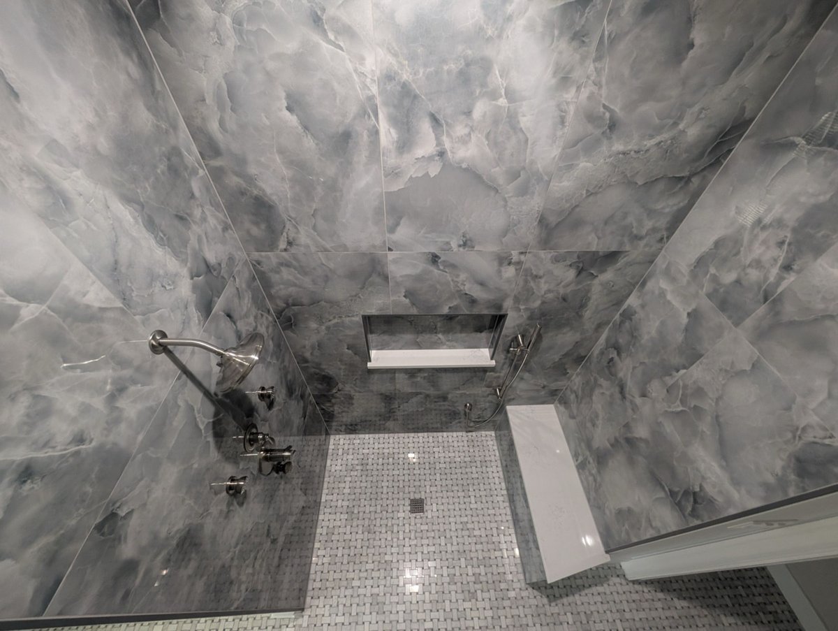 Smoky gray marble shower walls with niche and basketweave floor tile