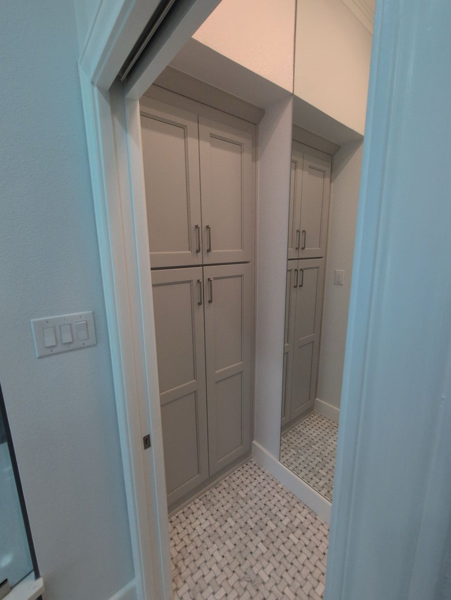 Gray shaker linen cabinets reflected in mirror over basketweave tile floor