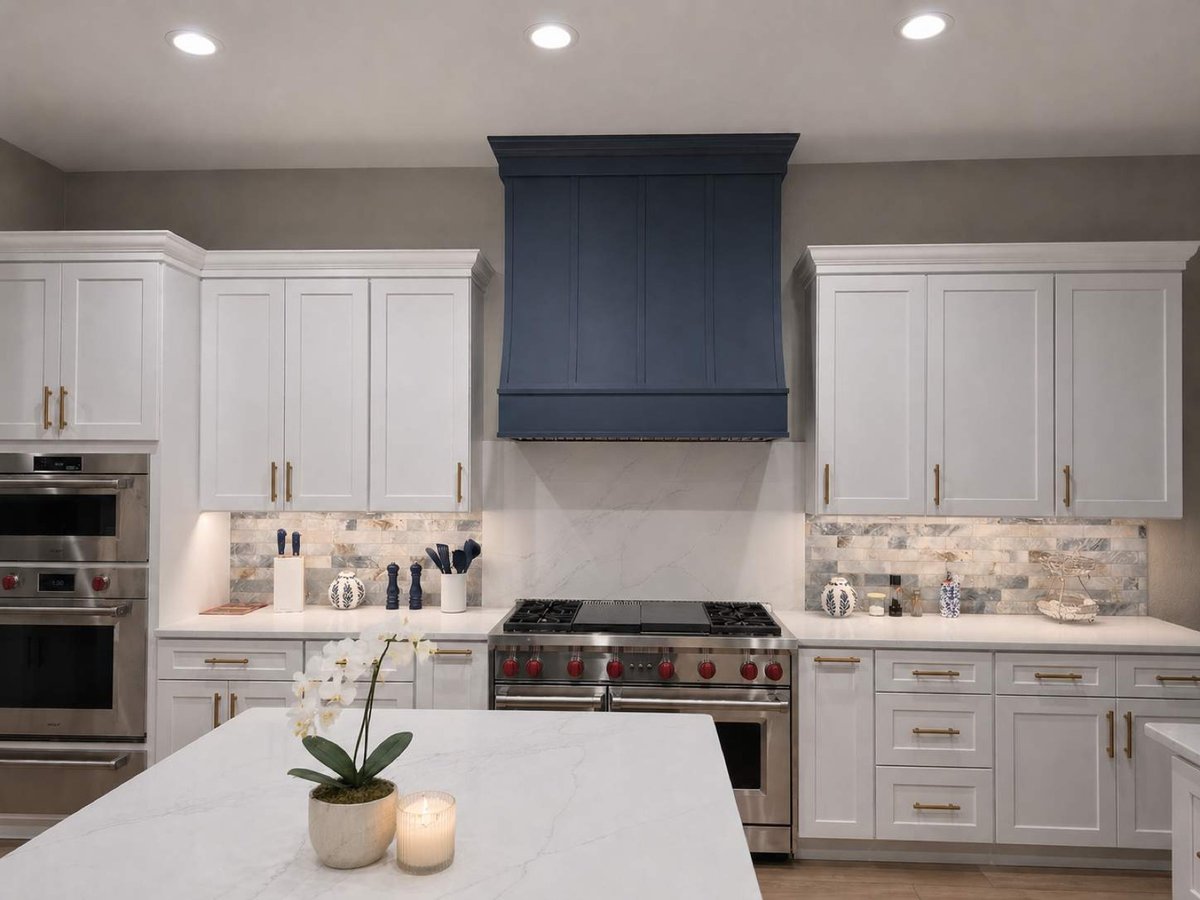 White cabinets with navy vent hood, stone backsplash and red-knob pro range
