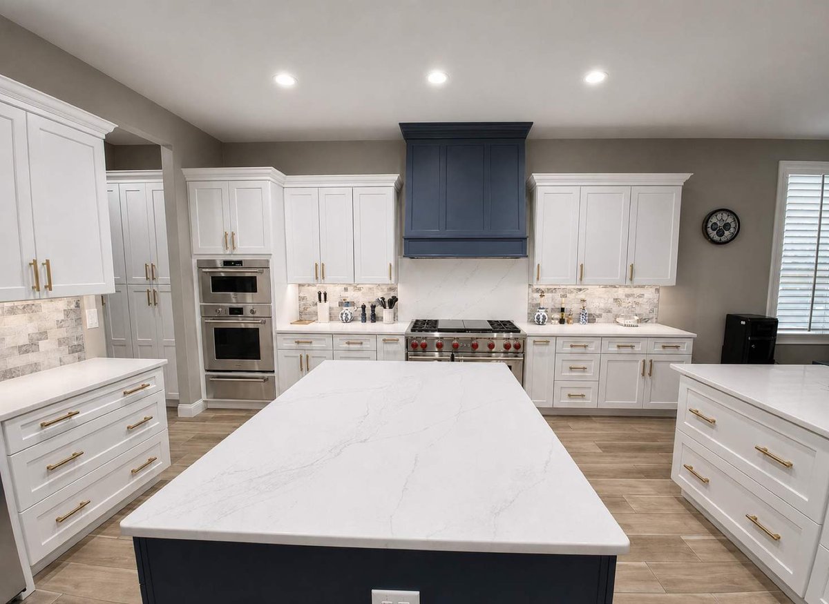 White kitchen with marble waterfall island, navy hood and double wall ovens