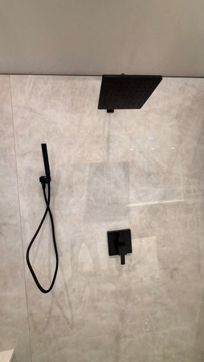 Black square rainfall showerhead and handheld sprayer on gray marble shower wall