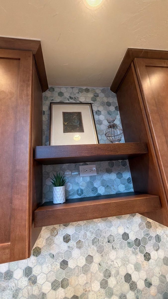Floating wood shelves with framed art over blue hexagon tile and mosaic floor