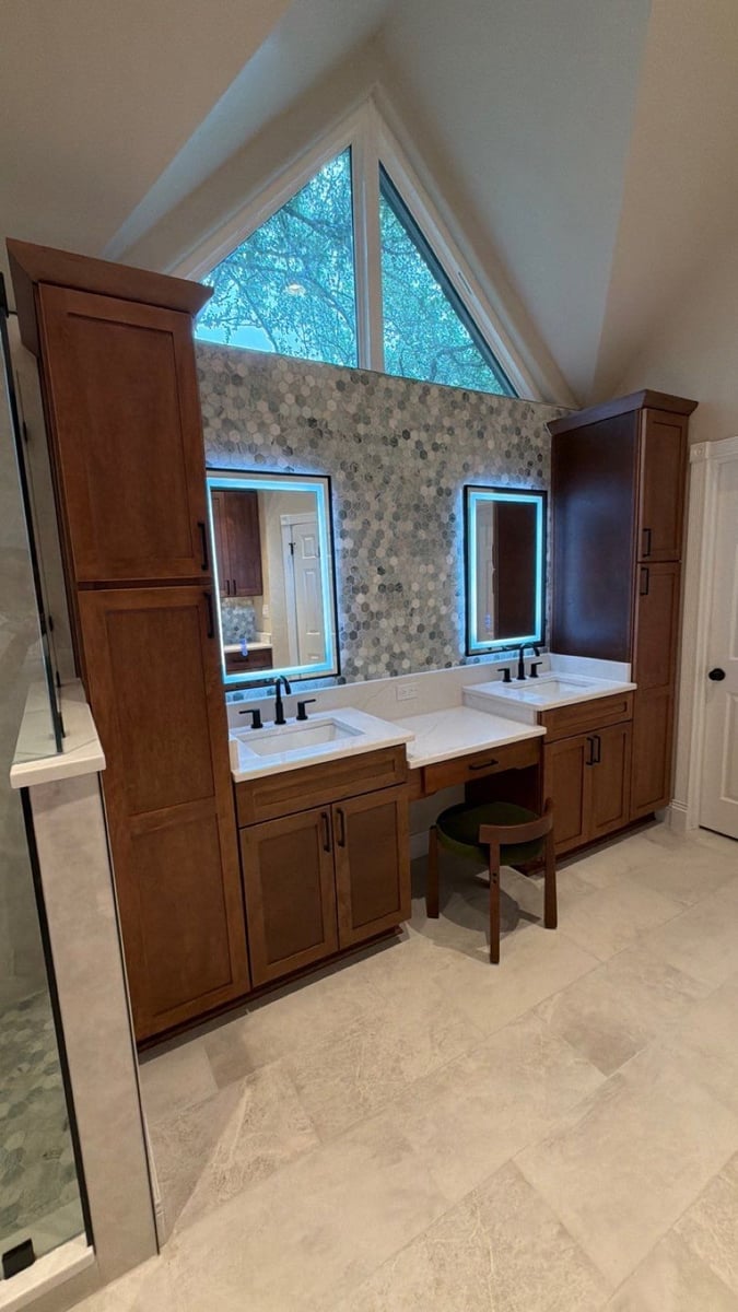 Double wood vanity with backlit mirrors under triangular window and hexagon backsplash