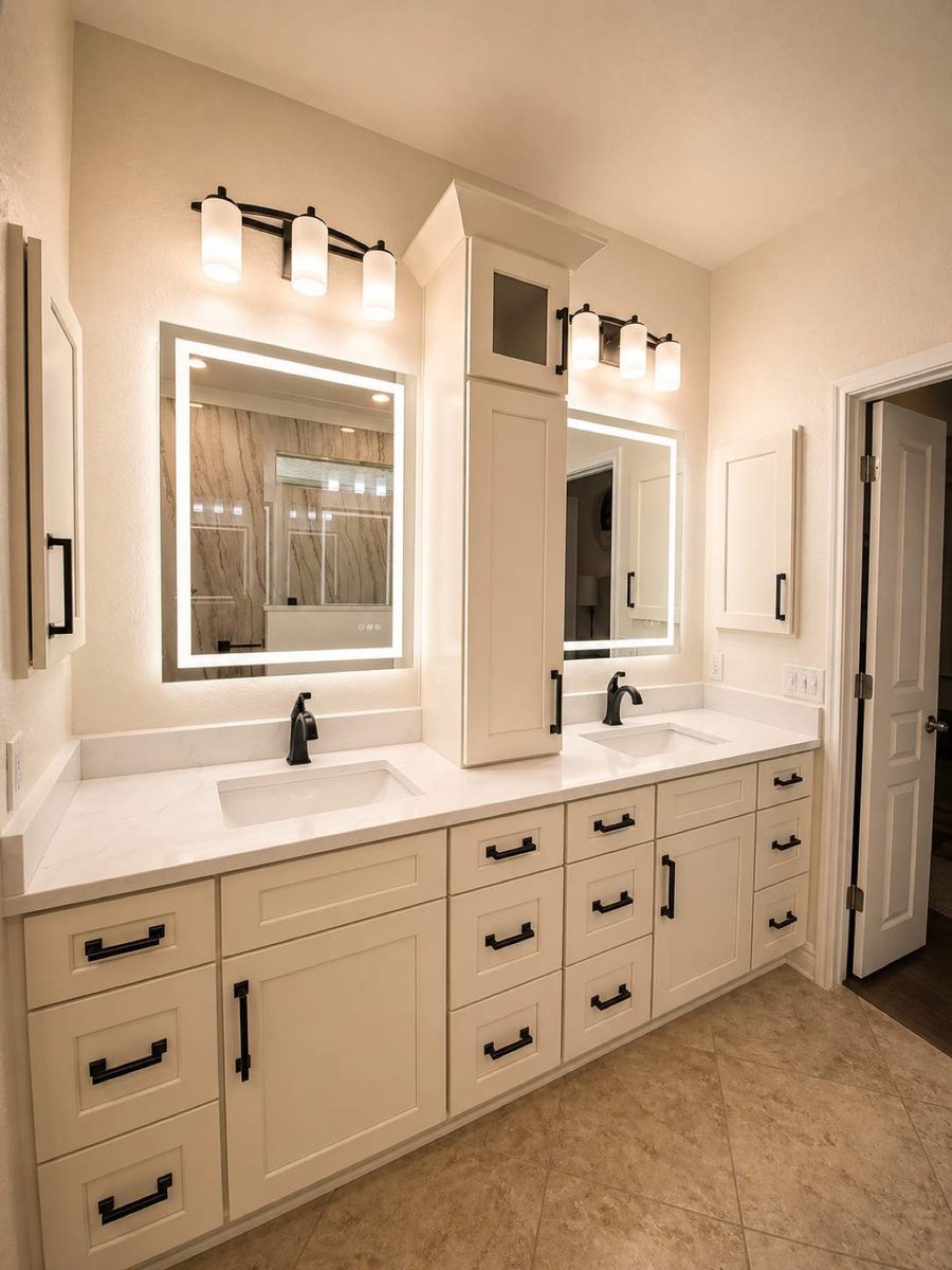 White double vanity with backlit mirrors, center tower cabinet and black faucets