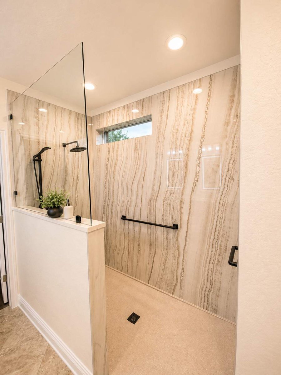 Curbless shower with light veined walls, half wall, black rainfall head and grab bar