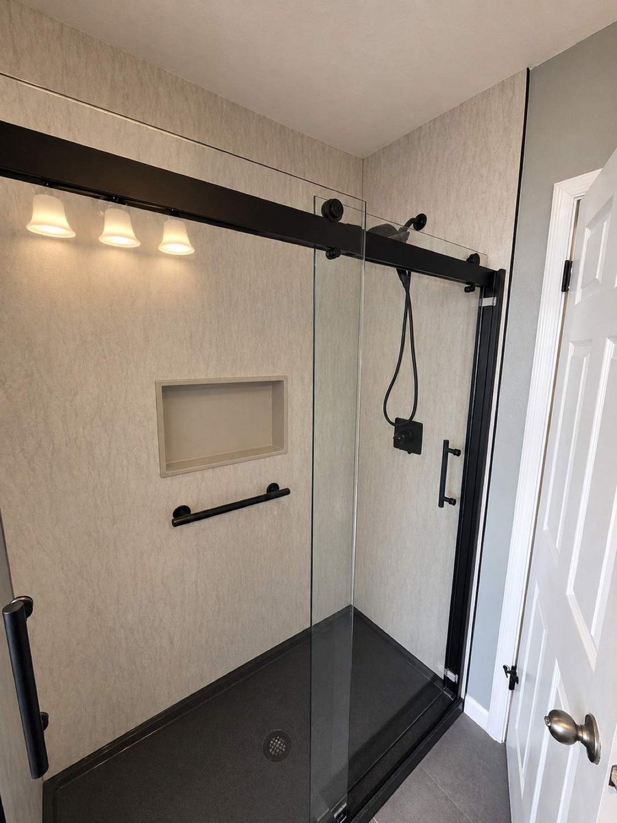 Walk-in shower with black-framed glass door and recessed niche