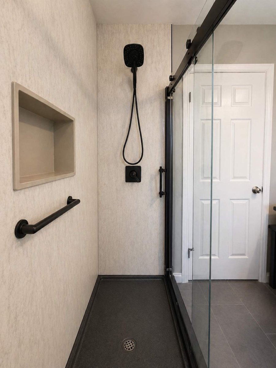 Black matte shower fixtures and niche on marble-look wall with dark base
