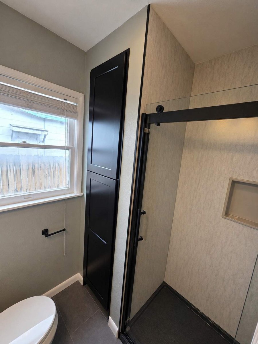 Black linen tower beside the glass shower under a window