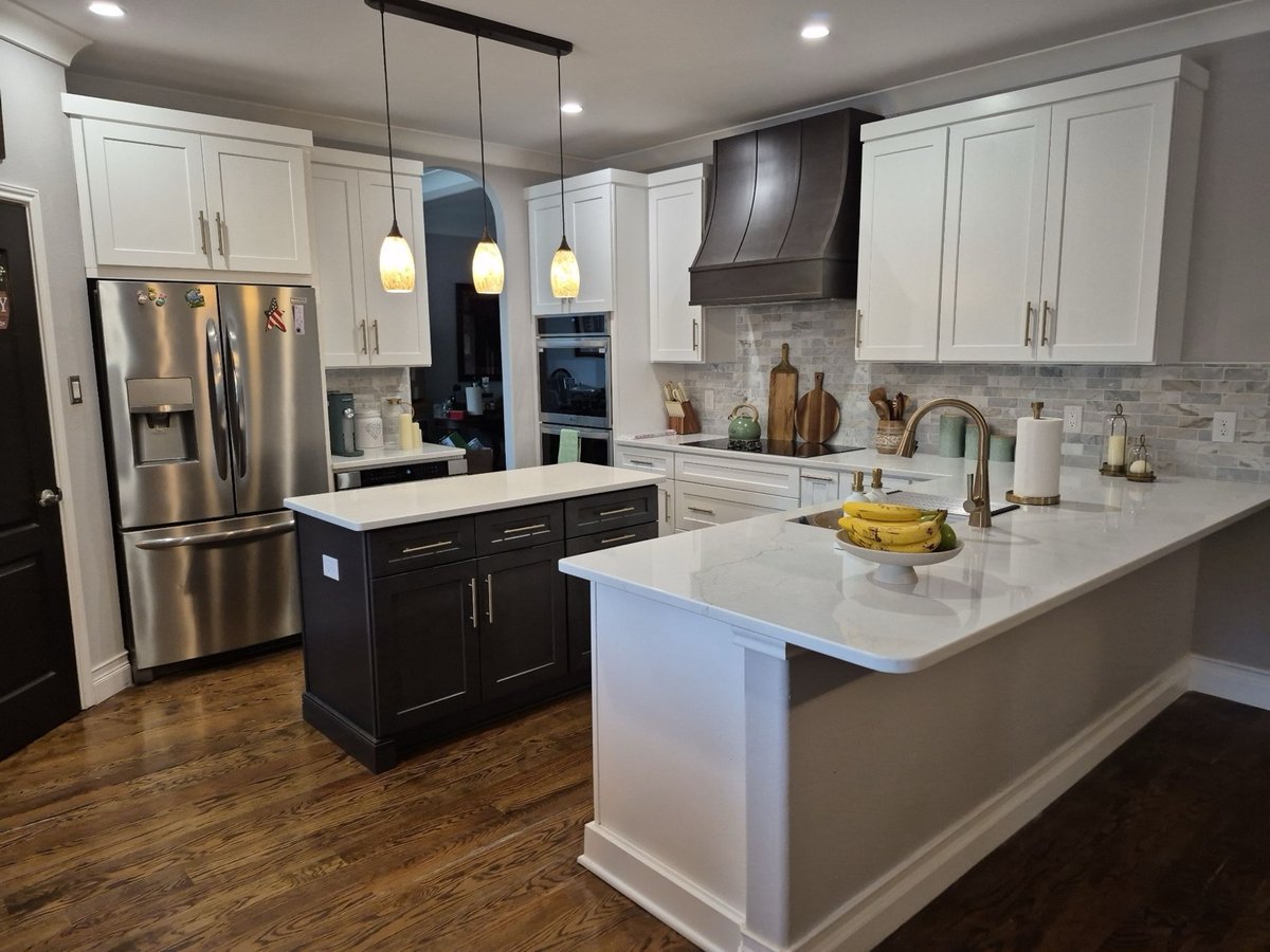 White and dark island kitchen with vent hood and brass faucet at sink