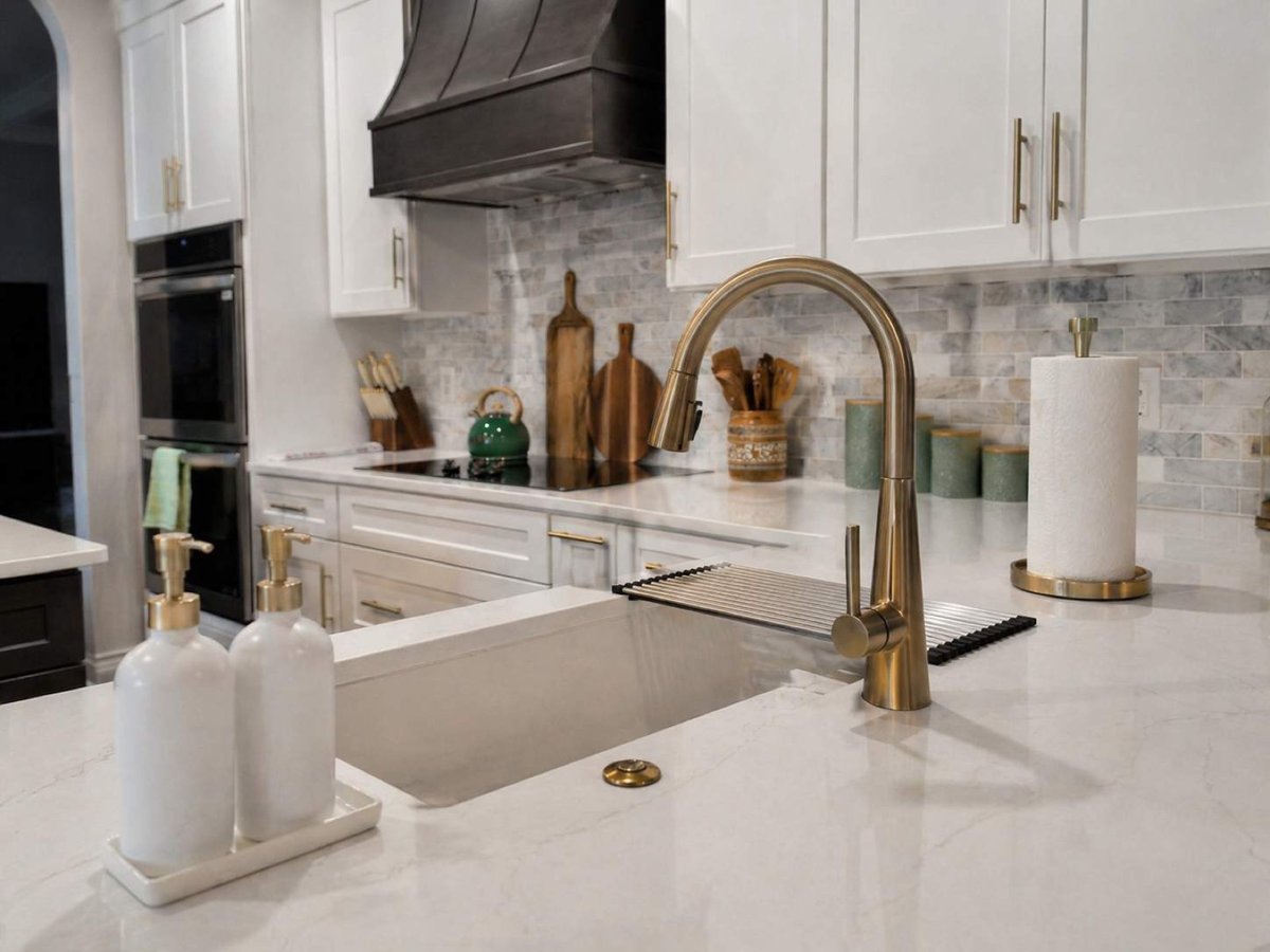 White kitchen with black hood, marble subway backsplash and brass fixtures