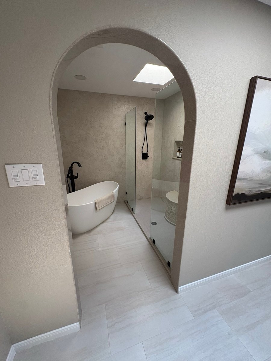 Arched doorway framing freestanding tub and glass shower with black fixtures