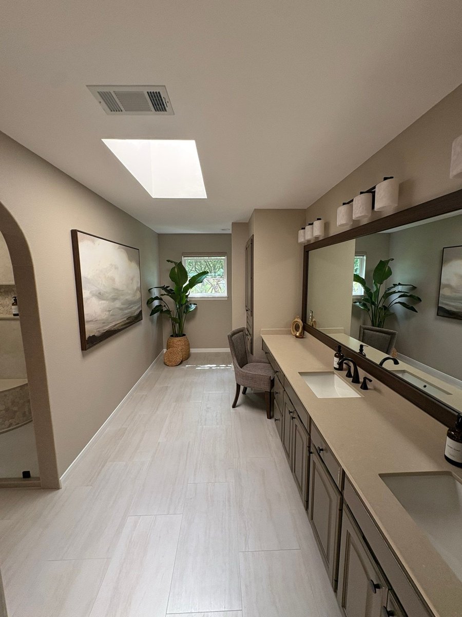Galley master bath with double vanity, framed art and arched shower entry