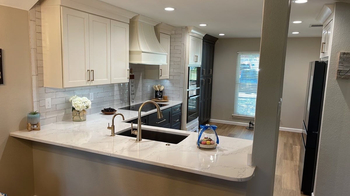 Peninsula with quartz counter, black sink and dark induction range beyond