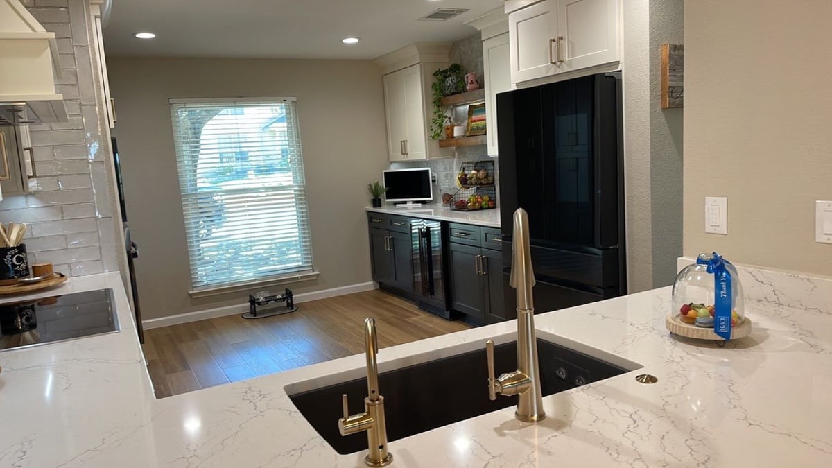 View over black undermount sink toward coffee bar and black refrigerator