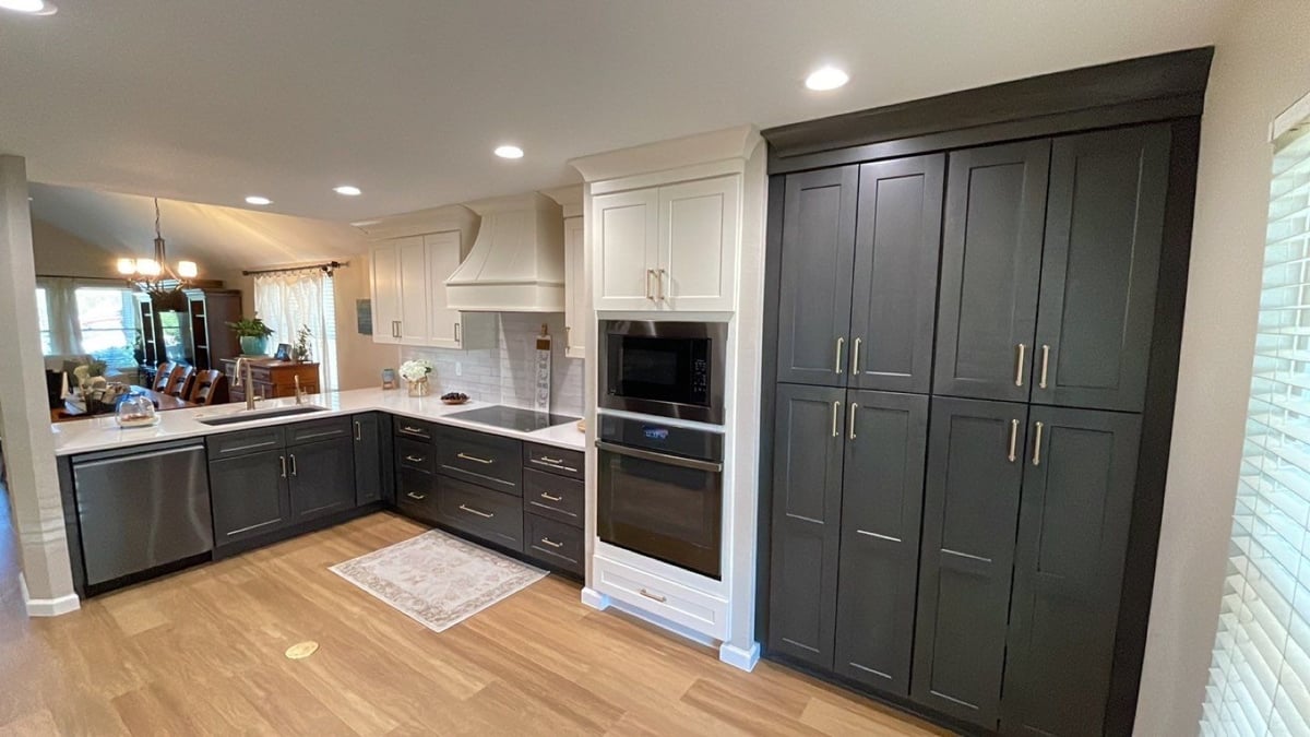 Kitchen with tall dark green pantry cabinets, white hood and wall oven