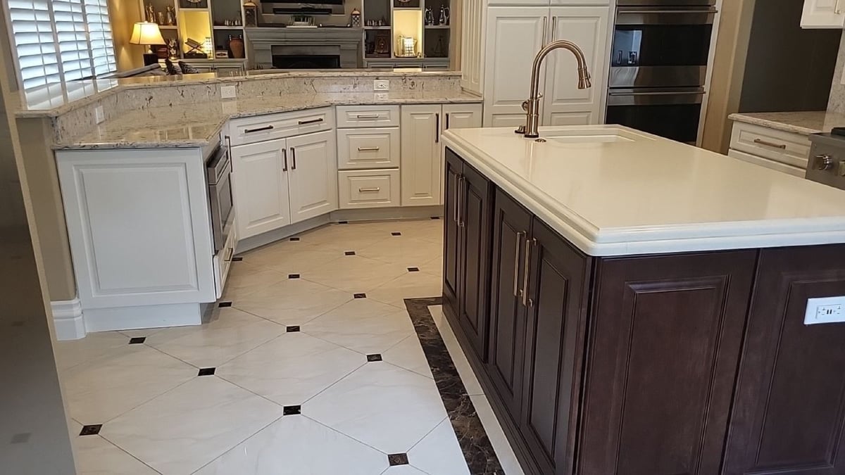 White perimeter cabinets with granite counters and dark island with patterned tile floor