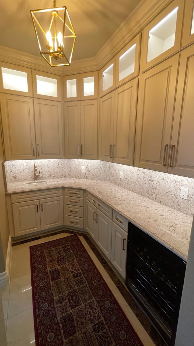 Butler pantry with cream cabinets, granite counters, wine fridge, and lantern pendant