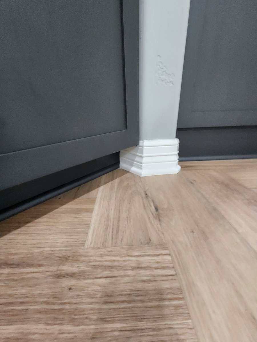 White column base set against charcoal cabinetry on wood-look flooring