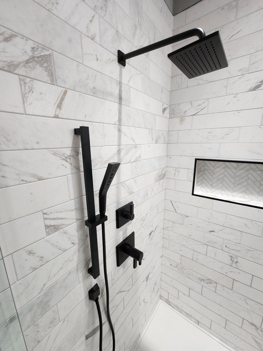 Marble shower wall with black rainfall head, handheld wand and herringbone niche