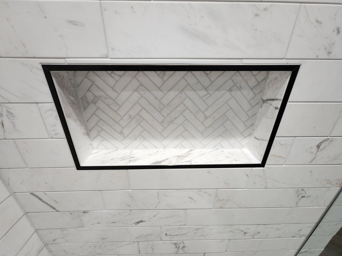 Black-framed shower niche set into marble subway tile