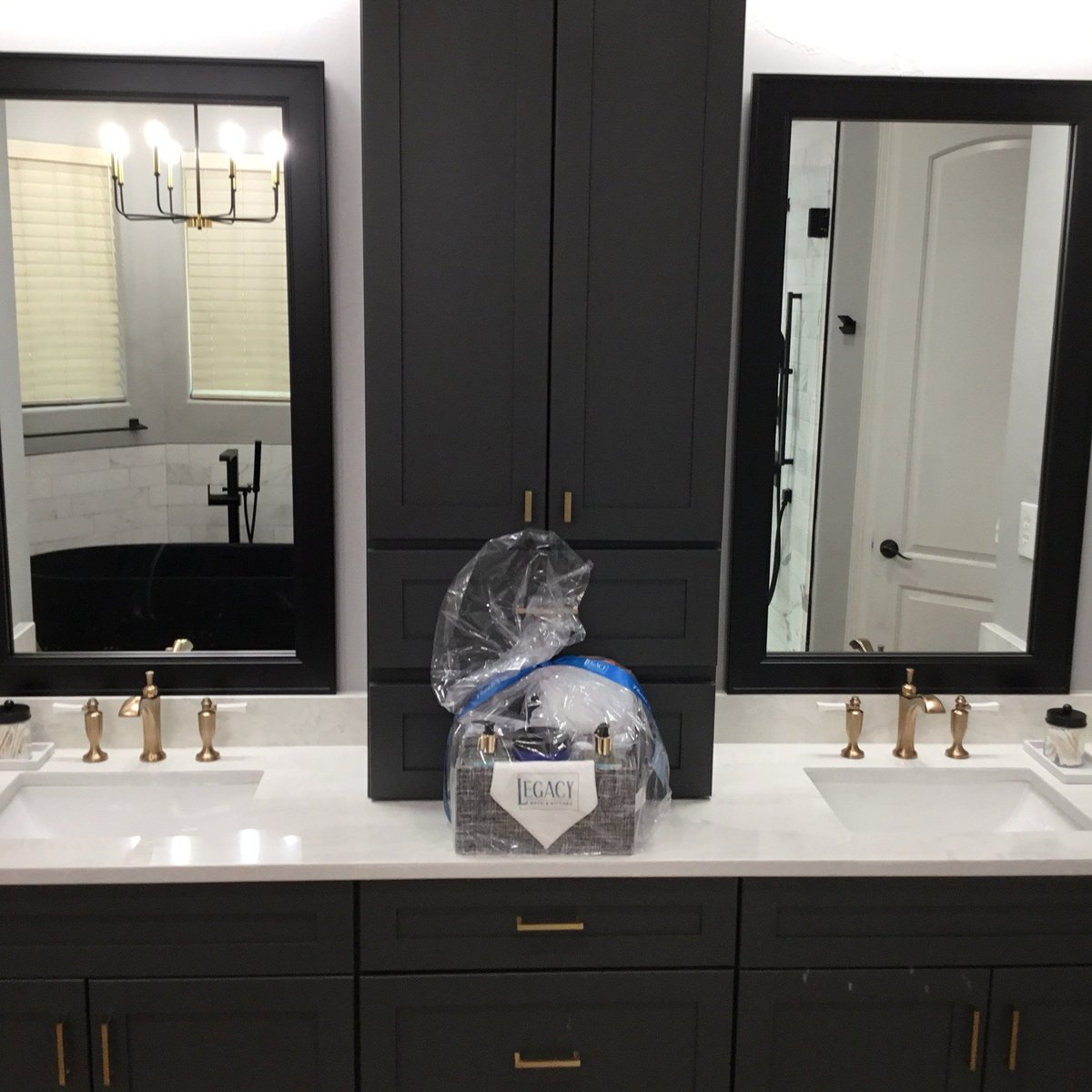 Charcoal double vanity with tower cabinet and gift basket between black mirrors