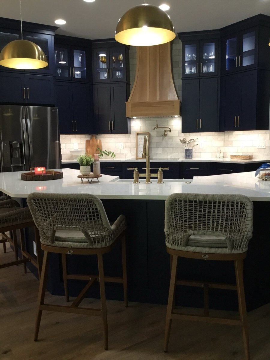 Navy kitchen with wood range hood, brass dome pendants and woven island stools