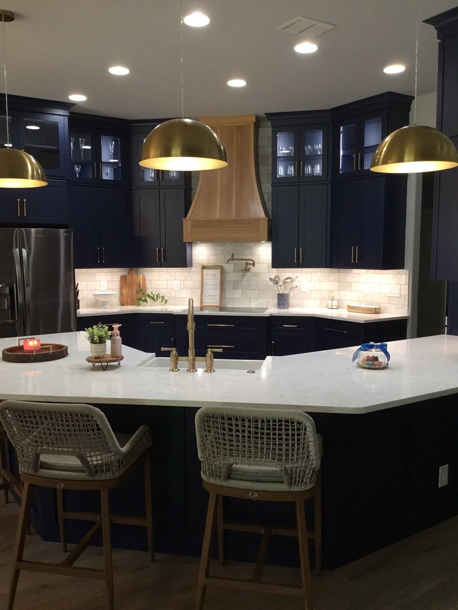 Navy cabinet kitchen with wood hood, white quartz island and brass dome pendants