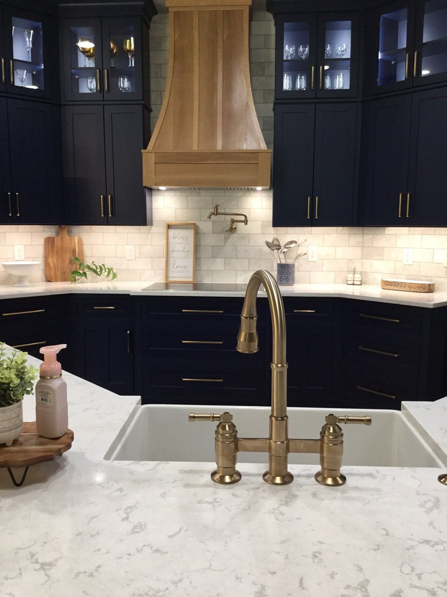 White quartz countertop with blue-ribboned gift plate in navy and brass kitchen