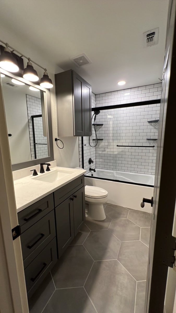 Gray cabinet bathroom with subway-tiled tub-shower and hexagon tile floor