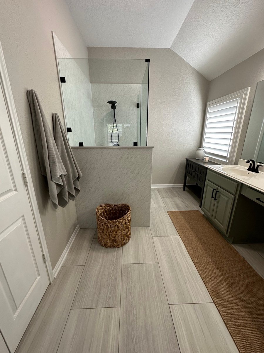 Remodeled bath with glass shower, green vanity, and wood-look tile floor