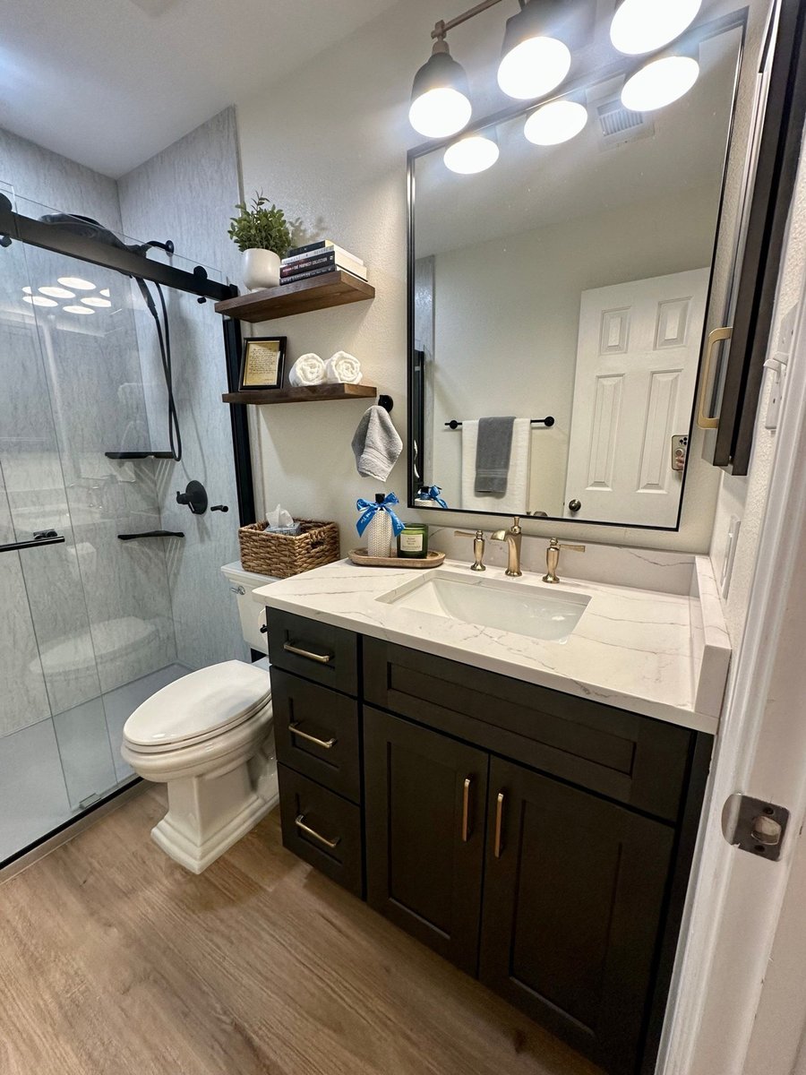 Bathroom with glass shower, dark vanity, framed mirror, and globe vanity lights