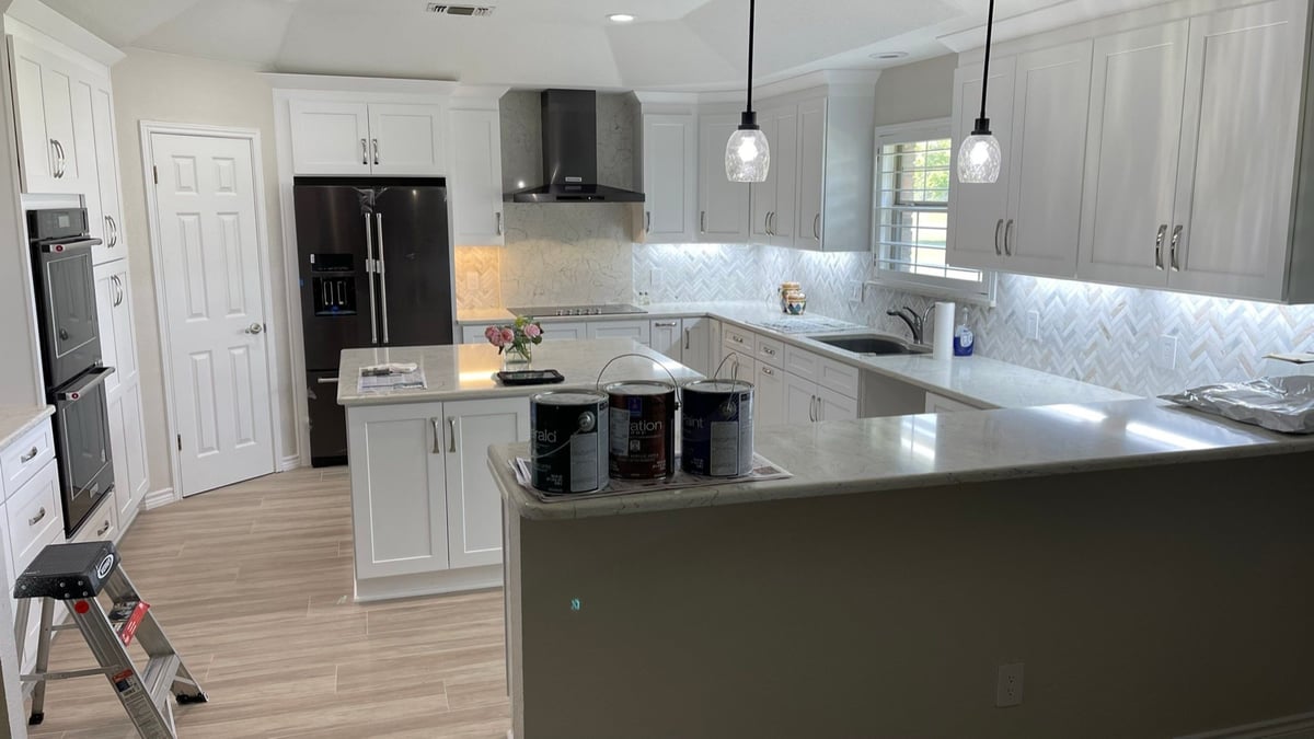 Remodeled white shaker kitchen with herringbone backsplash and black appliances