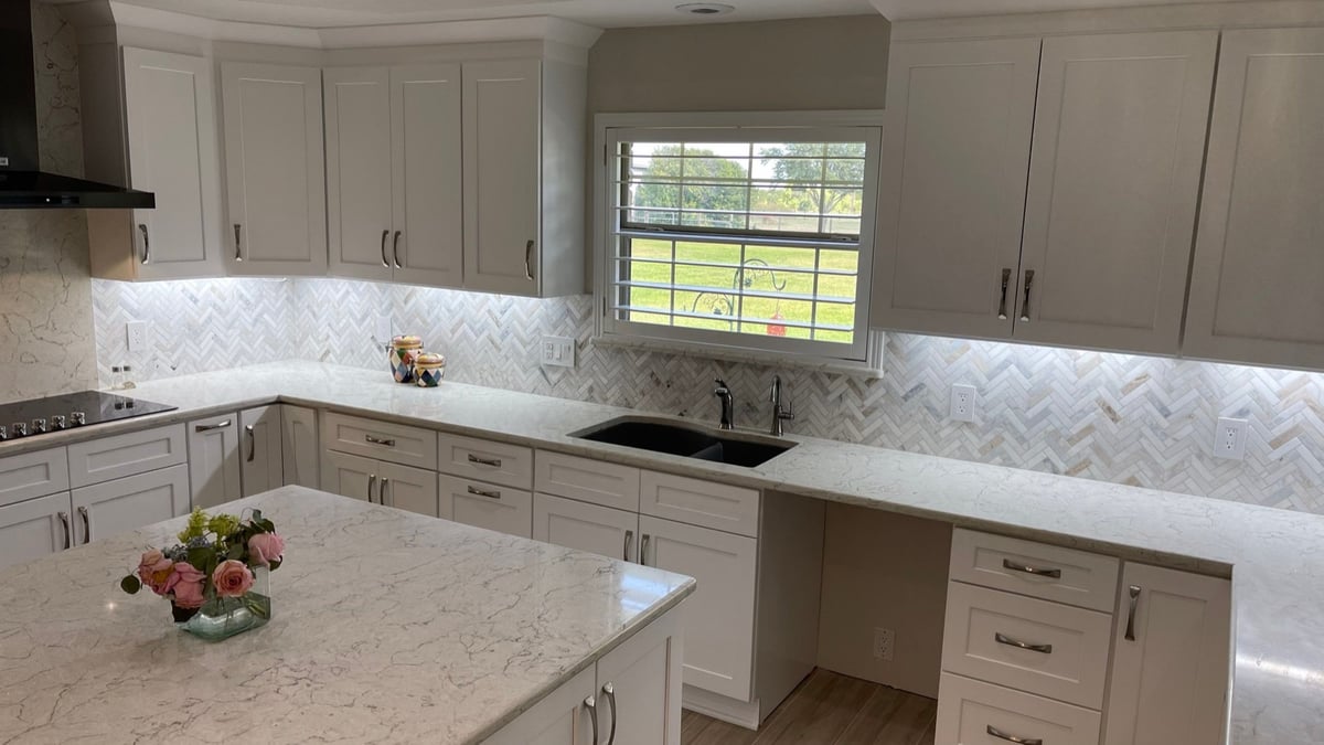 U-shaped white kitchen with center island, black fridge and pendant lighting