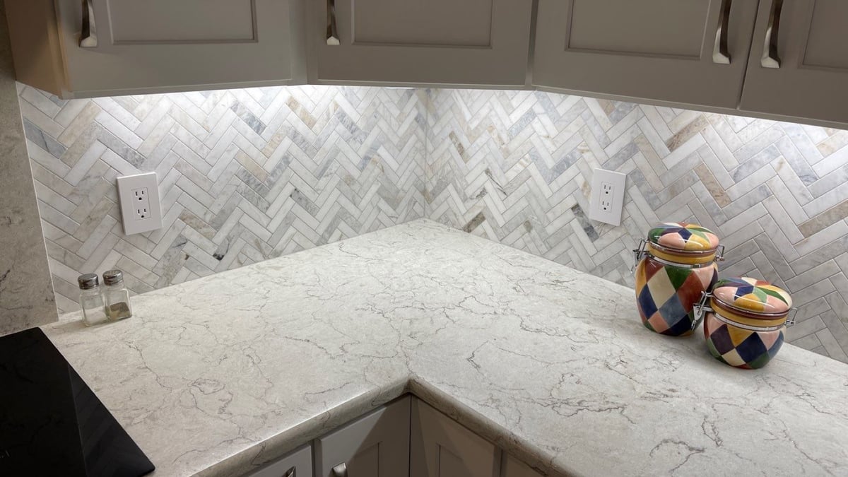 Corner counter with herringbone backsplash, quartz top and colorful canisters
