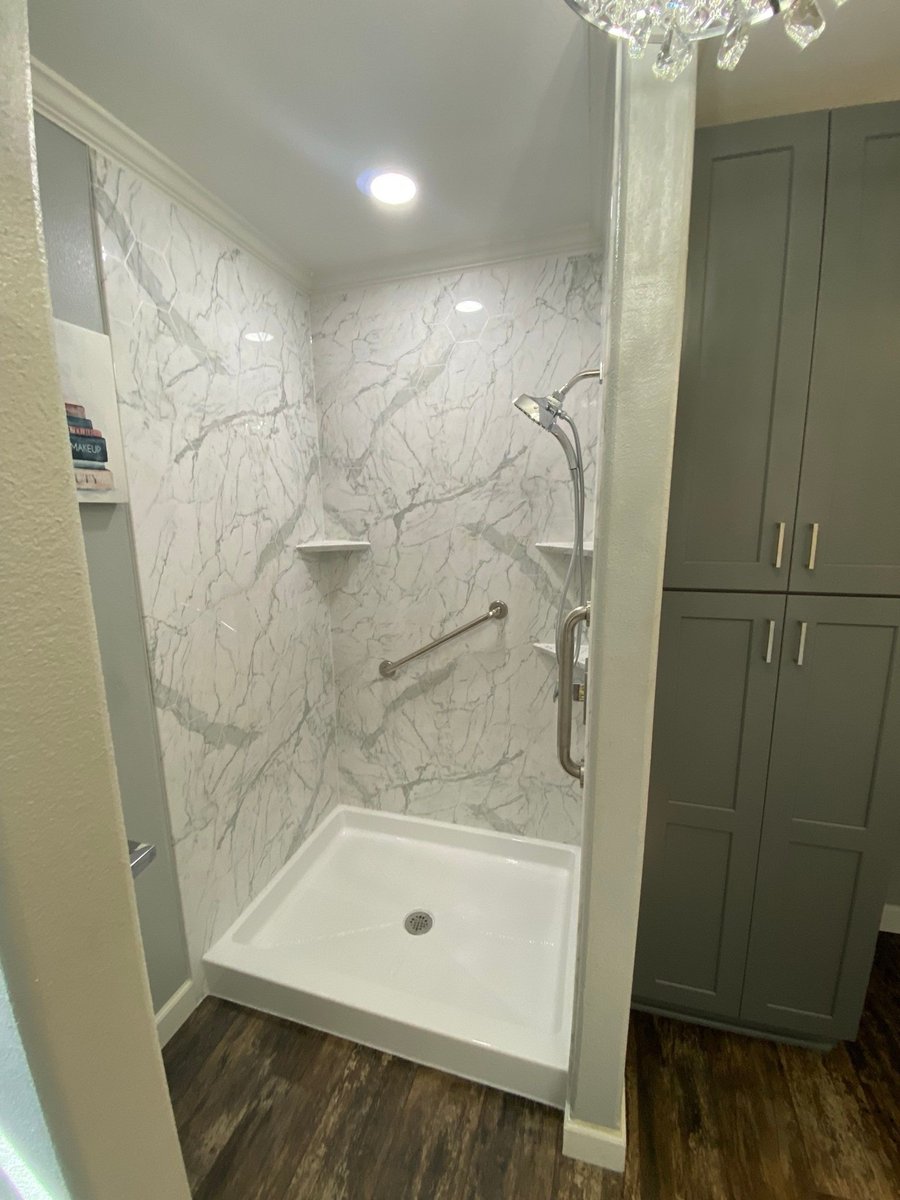 Walk-in shower with white marble walls, grab bars and low threshold pan