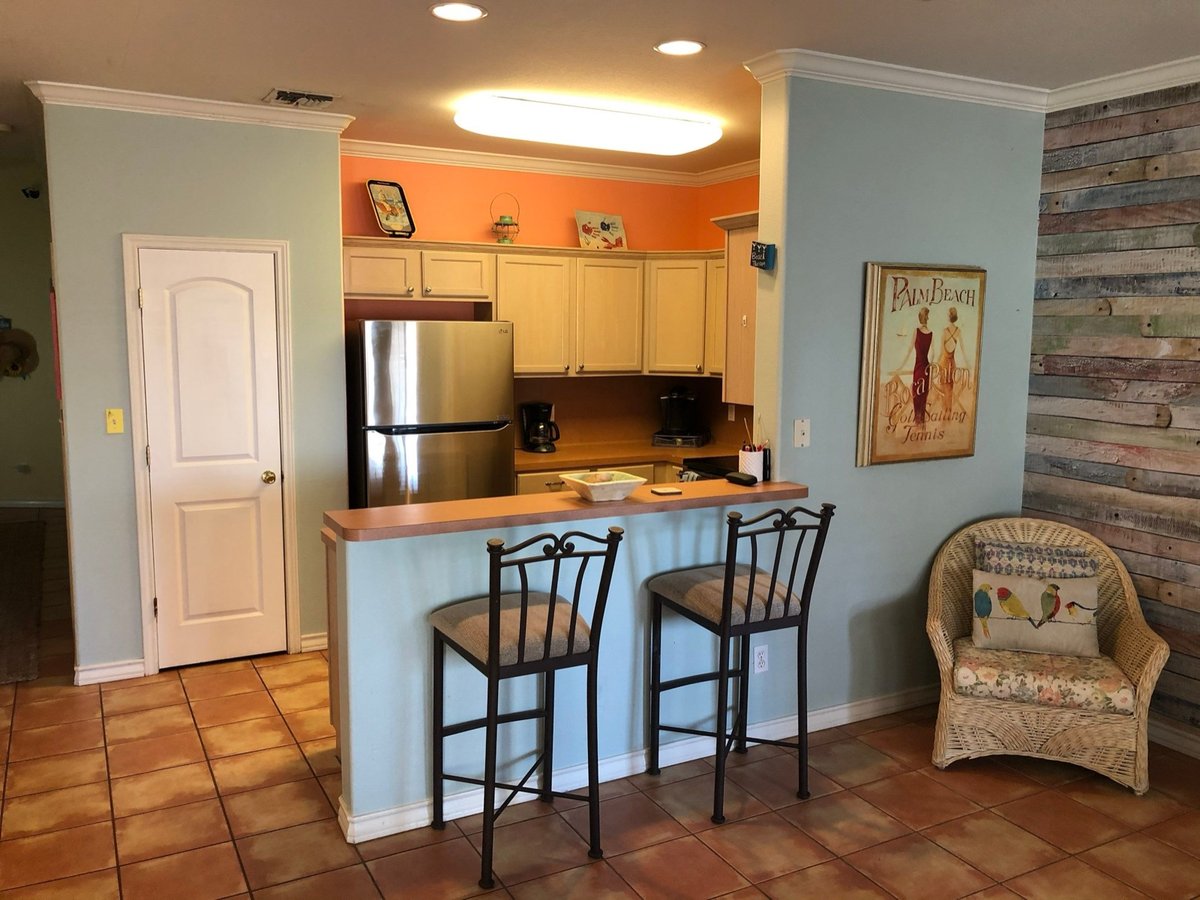 Dated kitchen with cream cabinets, laminate peninsula, and metal barstools