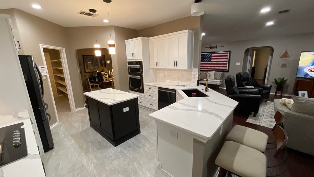 Kitchen open to living room with black island, white cabinets, and US flag