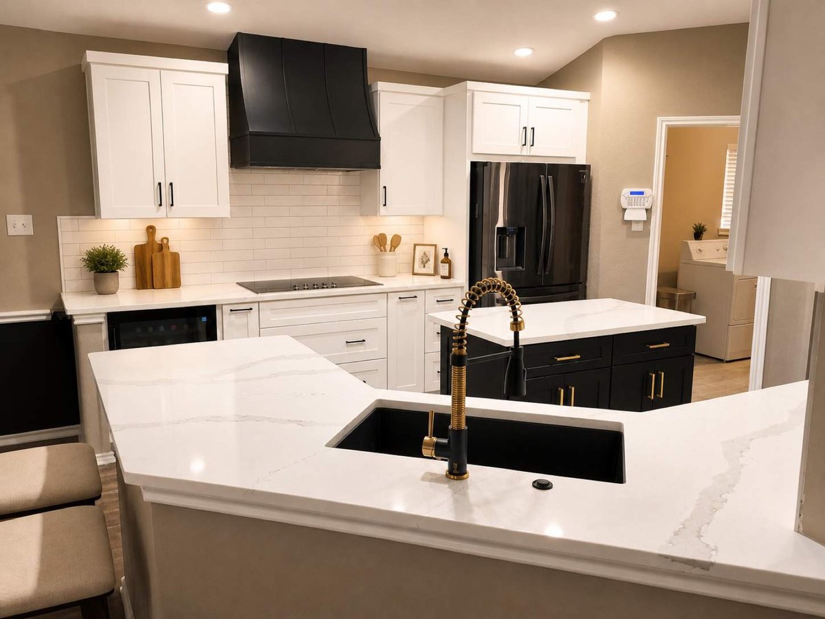 Quartz peninsula with black sink and gold faucet facing white cabinets and black island