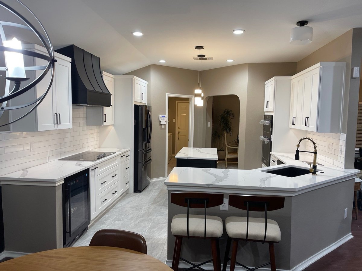 White kitchen with black hood, peninsula seating, and orb chandelier