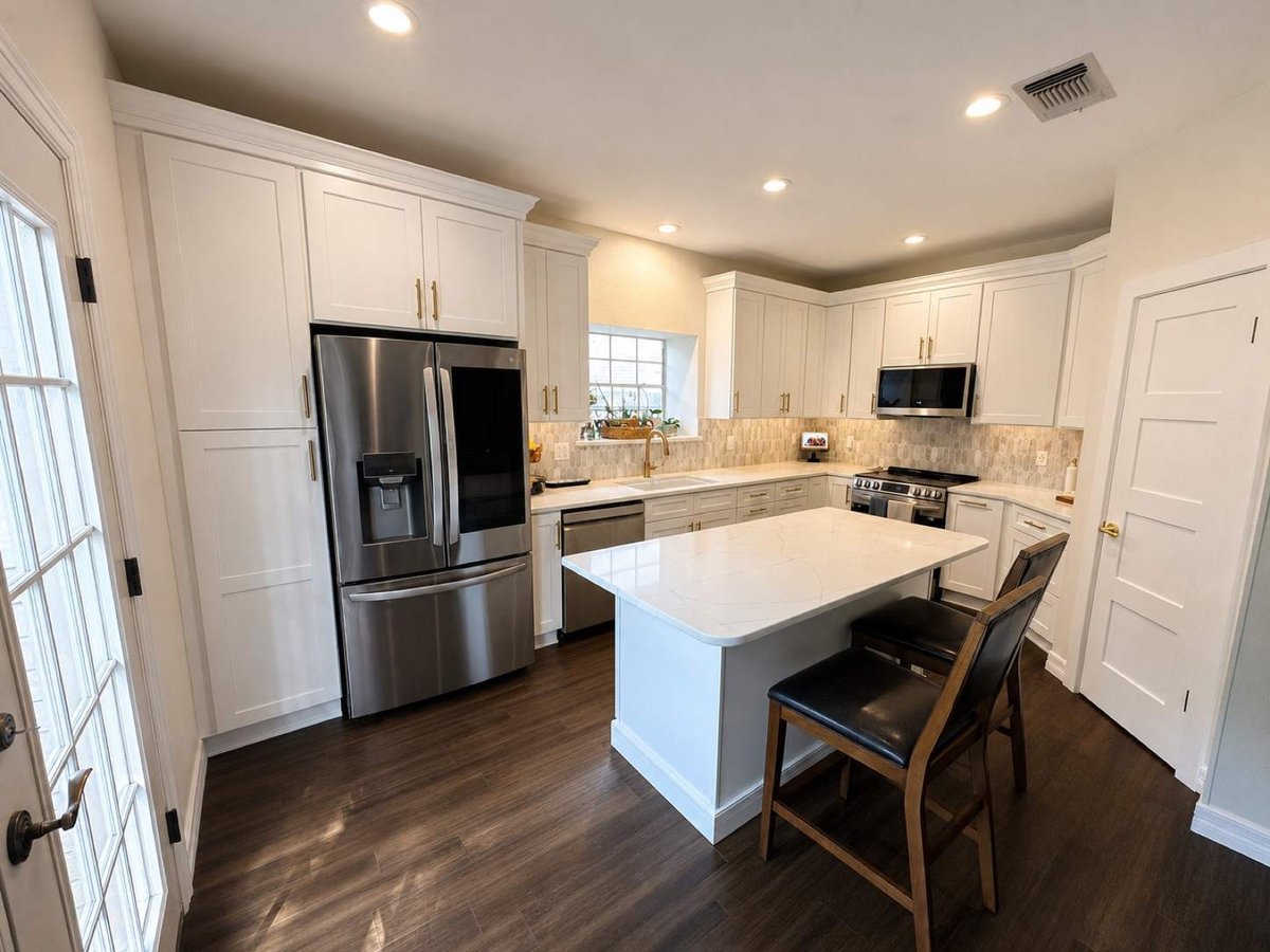 Bright white kitchen with center island, dark wood floors, and marble picket backsplash