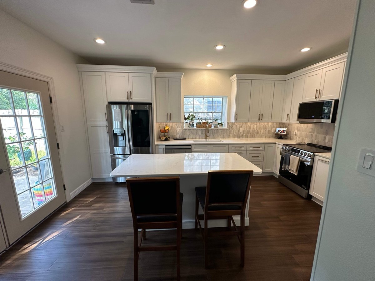 Kitchen with white cabinets, stainless range, and quartz island counter
