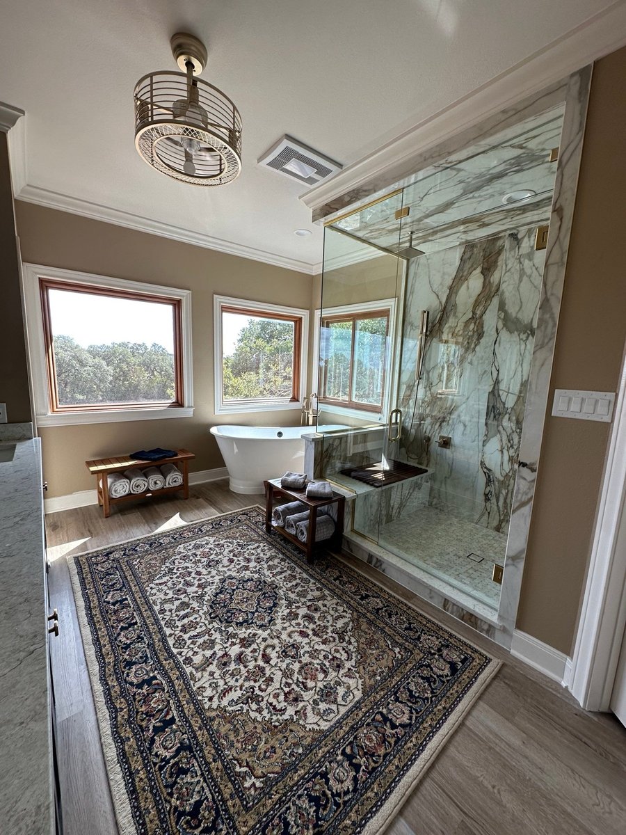 Spa-style master bath with soaking tub, marble shower, and Persian rug
