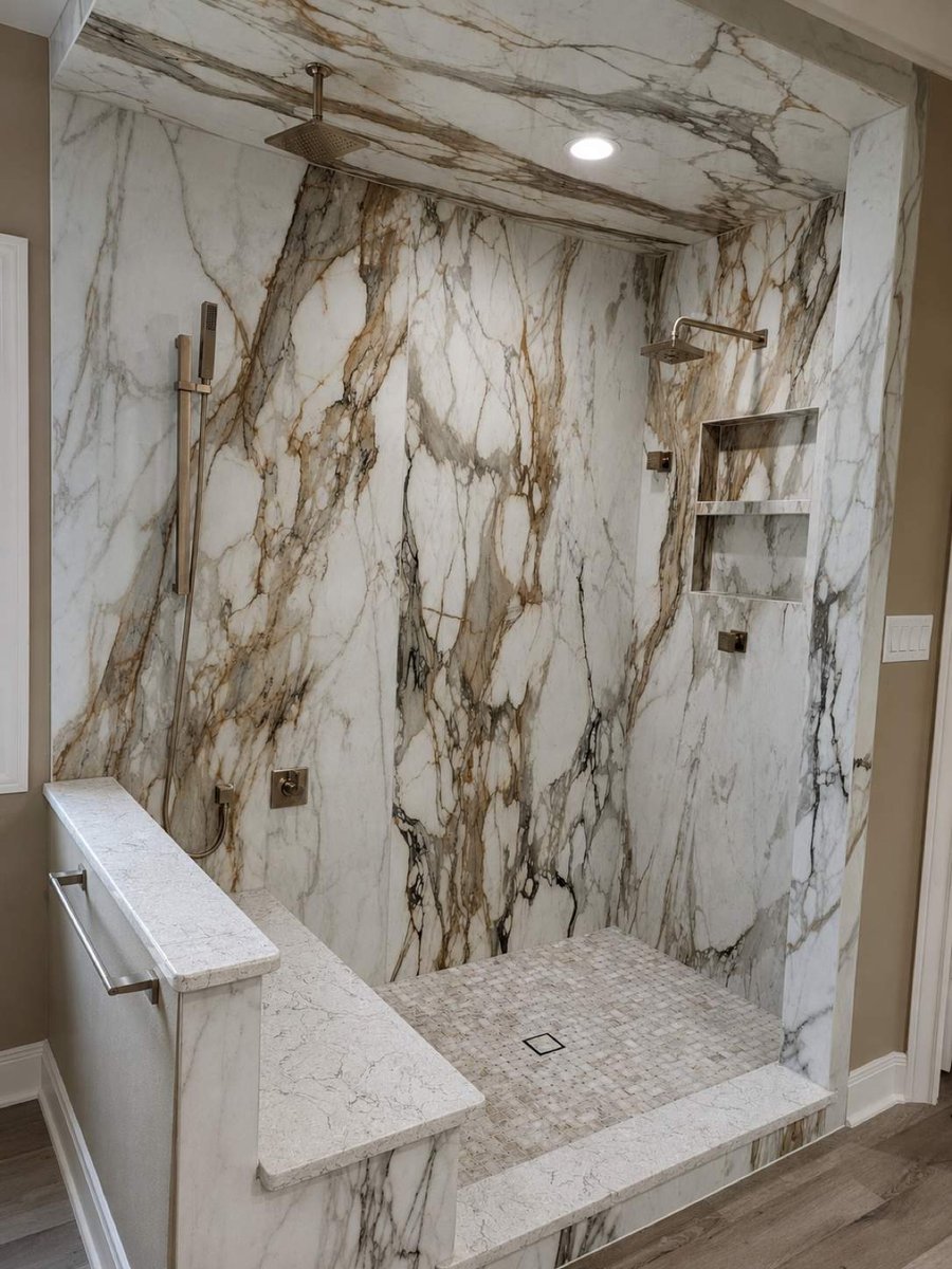 Dramatic veined marble shower with rainfall head and built-in bench seat
