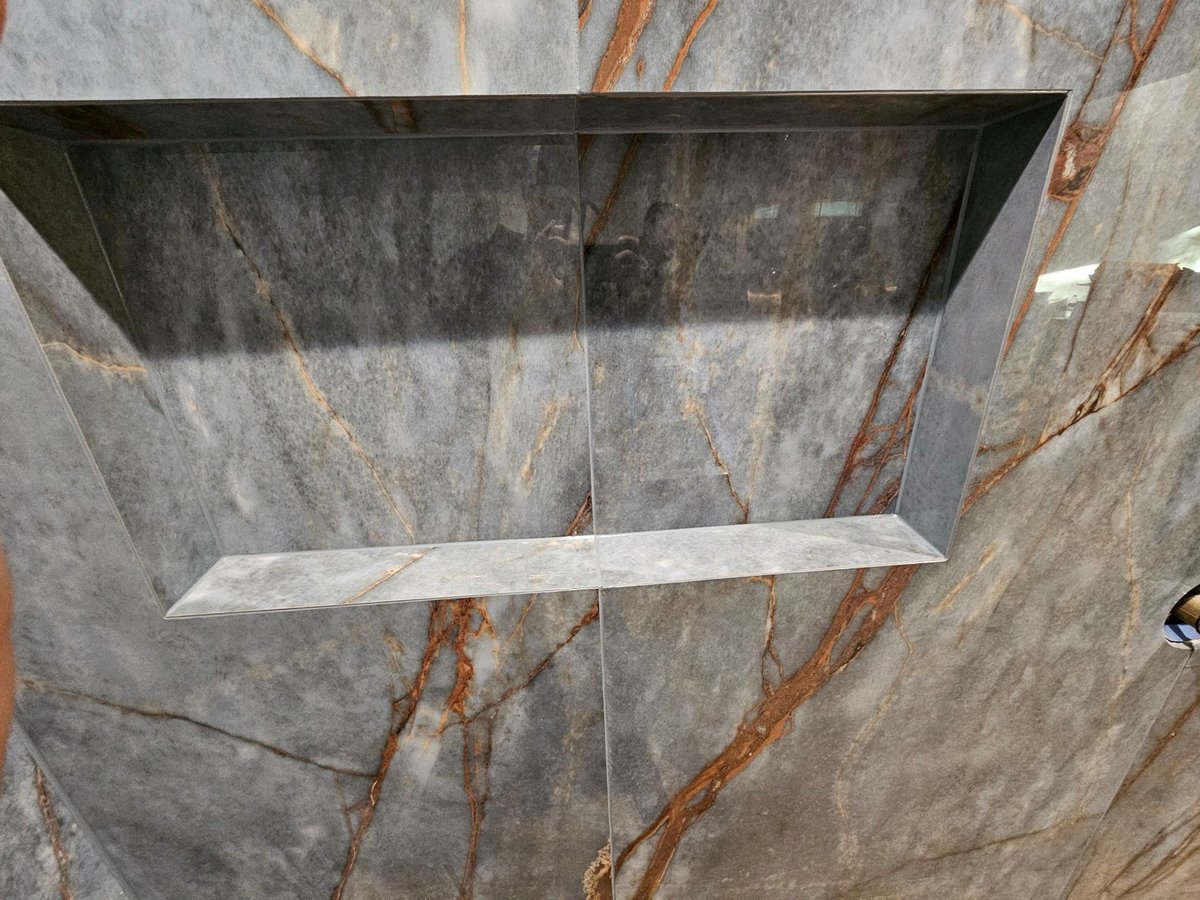 Close-up of recessed shower niche cut into gray marble slab tile